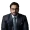Portrait of a man in a dark checkered suit and glasses looking at the camera with a neutral expression