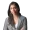 Professional woman with long dark hair wearing a black and white patterned blazer and white top smiling at the camera