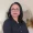 Portrait of a middle aged woman with dark hair and glasses wearing a black button up shirt standing indoors