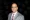 Yad Senapathy1200800 The Portfolio The Portfolio Professional head and shoulders portrait of a man in a gray suit white shirt and red blue plaid tie against a dark background with portfolio watermark
