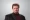 Blaine Little The Portfolio The Portfolio Professional headshot of a man with brown hair and goatee wearing a black blazer and burgundy turtleneck against a gray backdrop