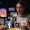 Woman with glasses at a desk surrounded by floating social media icons Instagram TikTok Facebook and interaction metrics