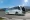 GreenCell Mobility Raised ₹330 Cr Expand Electric Bus The Portfolio White NuGo tour bus driving on a mountain road under a clear blue sky The Portfolio Magazine watermark in the top left corner